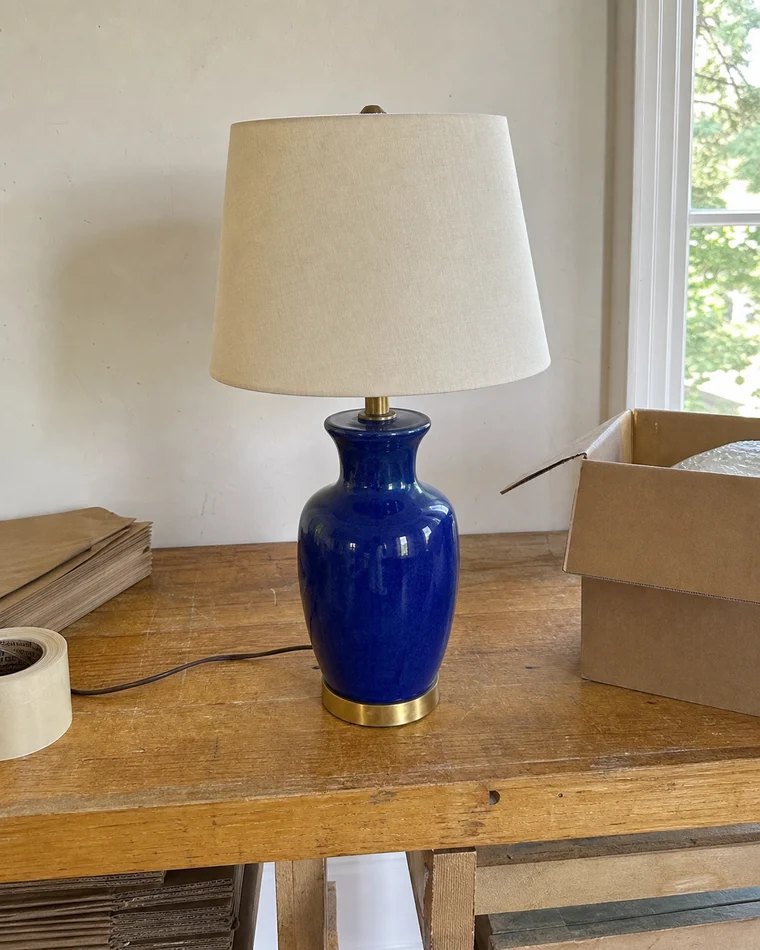 Casual phone photo of a cobalt-blue table lamp before AI studio enhancement